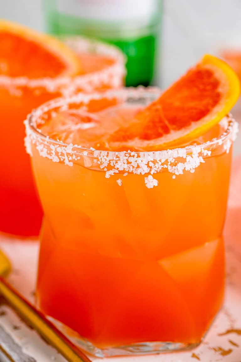 A salty dog cocktail with a salted rim and a fresh grapefruit slice garnish over ice in a rocks glass.