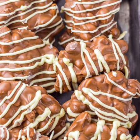 Crockpot Candy clusters drizzled with white chocolate on a metal tray.