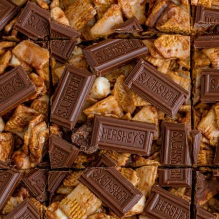 Golden grahams smores bars cut into squares and topped with Hershey's chocolate pieces.