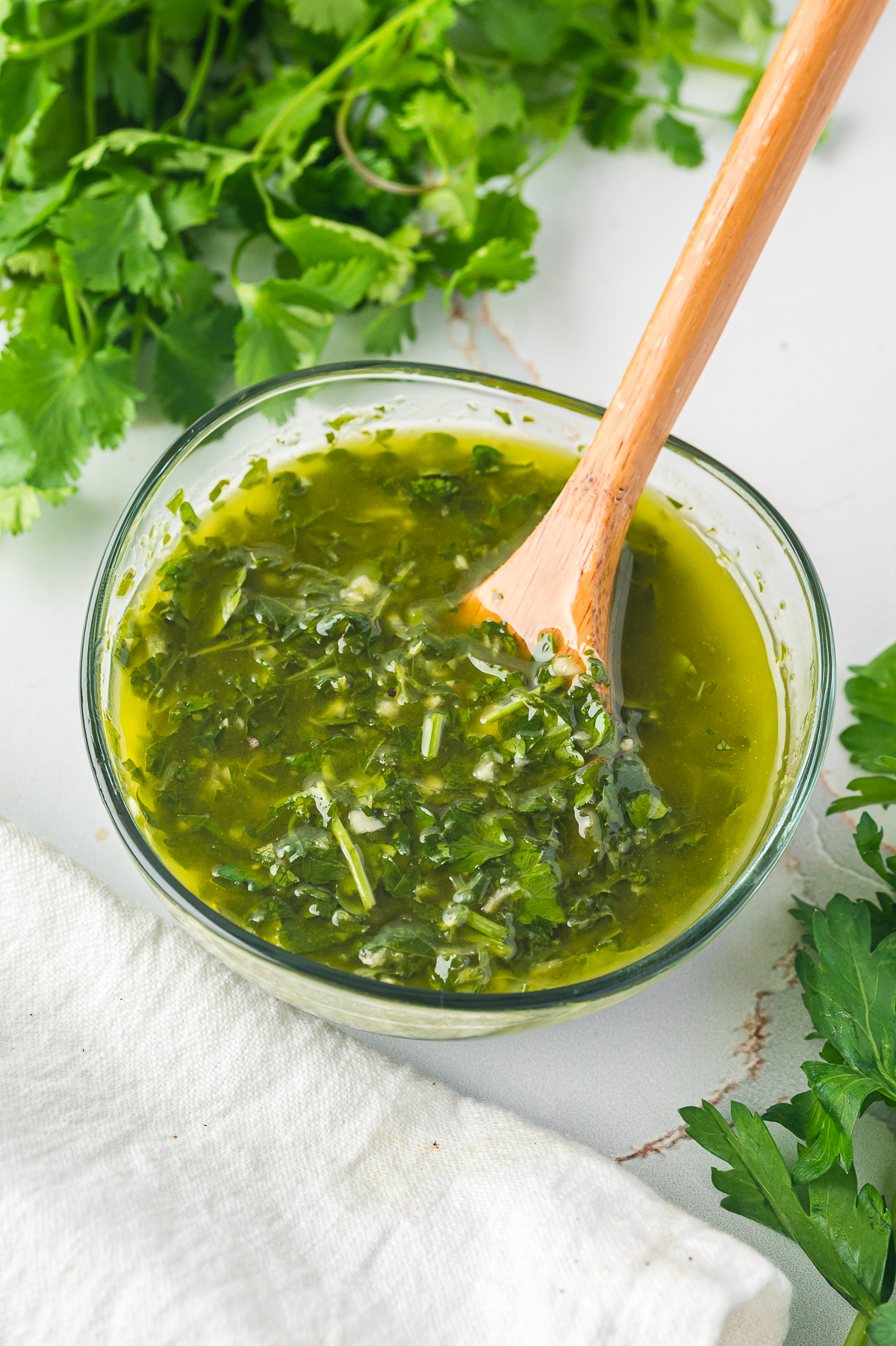 overhead image of chimichurri sauce in a bowl with a spoon in it