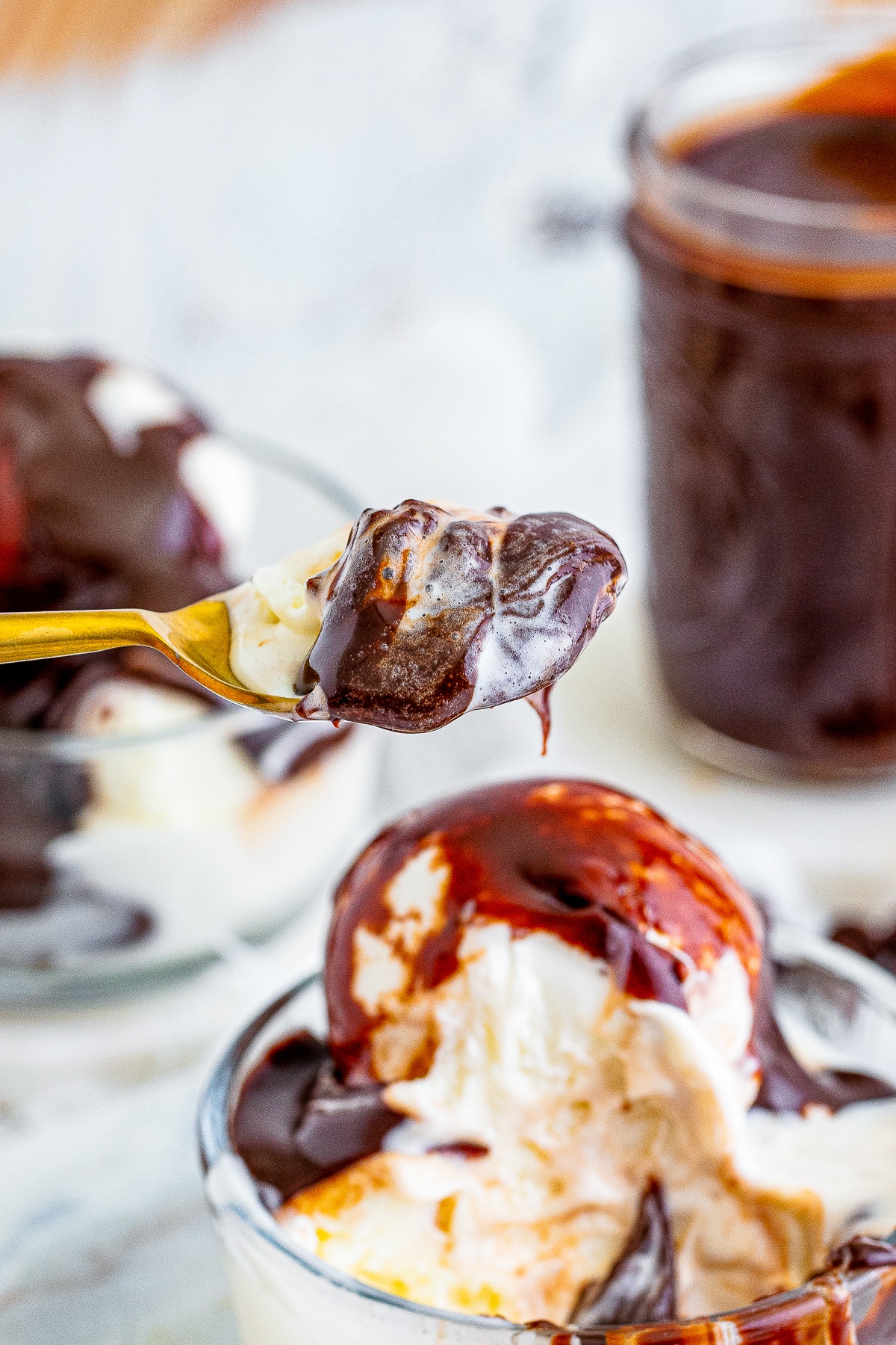a spoon holding up hot fudge with ice cream on a spoon in air