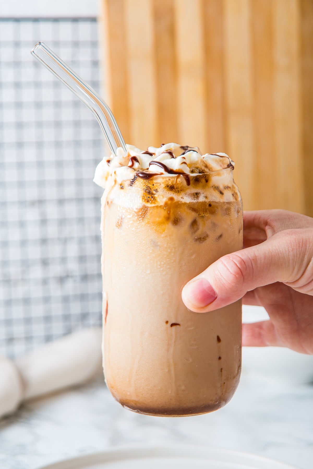 a hand holding up iced cafe mocha in air