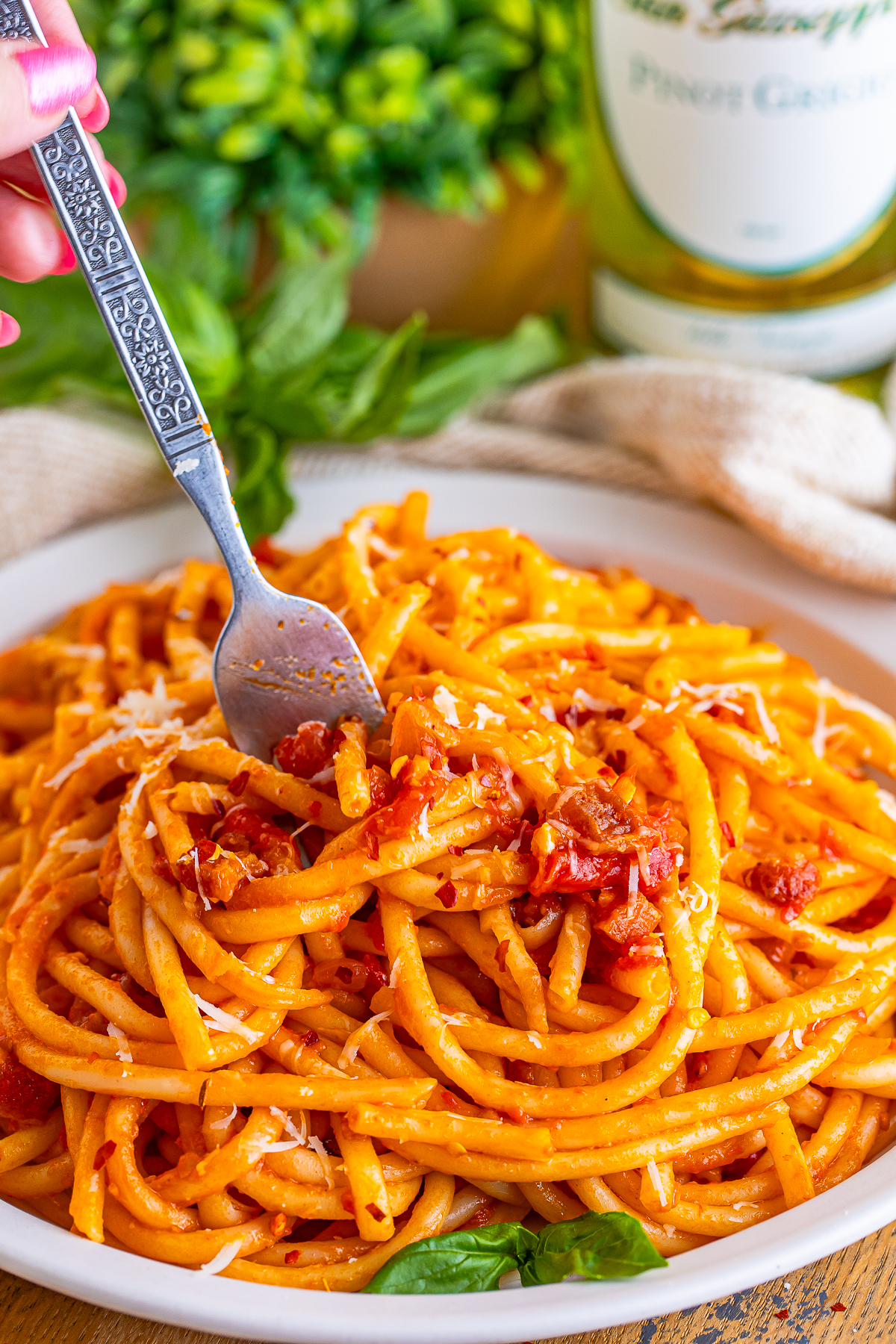 a fork digging into a plate of Bucatini all Amatriciana