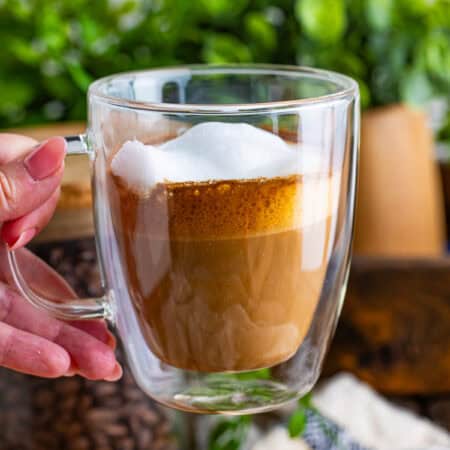 A glass mug of homemade flat white coffee with a layer of microfoam