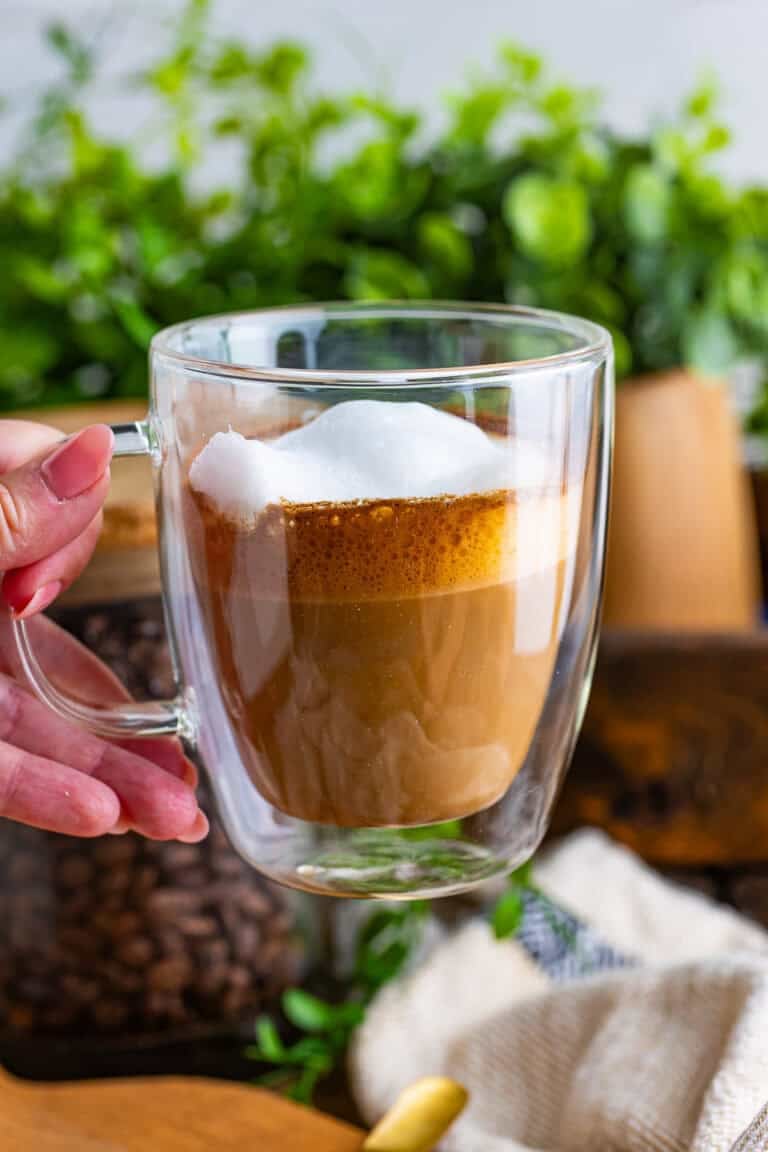 A glass mug of homemade flat white coffee with a layer of microfoam