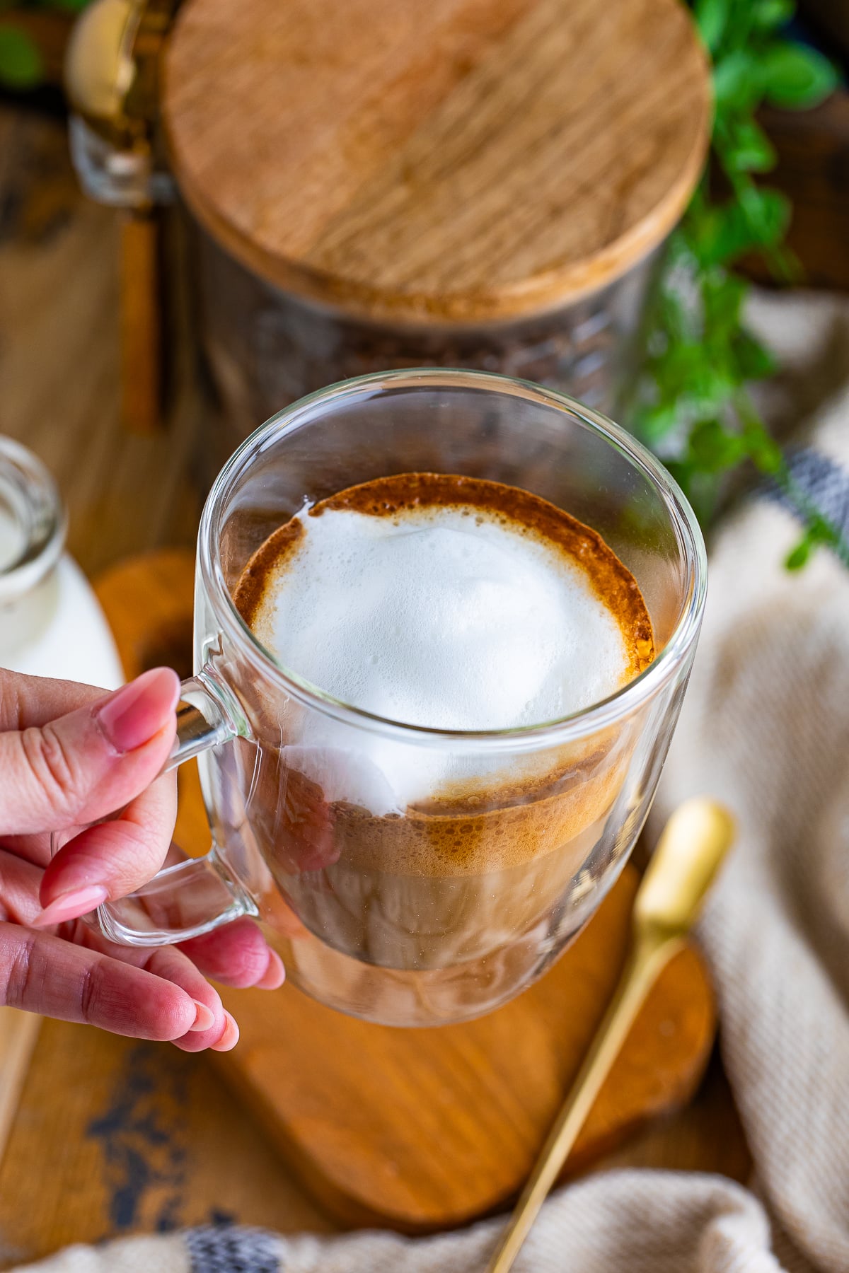overhead image of a hand holding a flat white in air