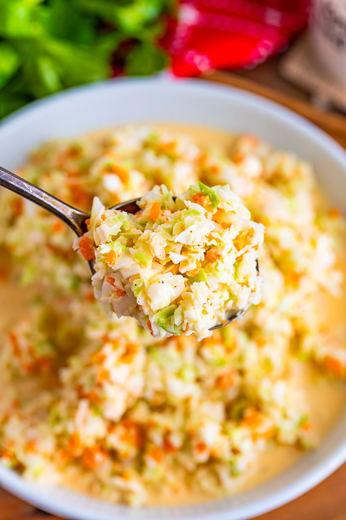 a spoon holding a bite of Kentucky Fried Chicken Coleslaw Recipe over white bowl