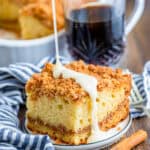 A slice of sour cream coffee cake with cinnamon crumble and a sour cream glaze drizzle on a plate.