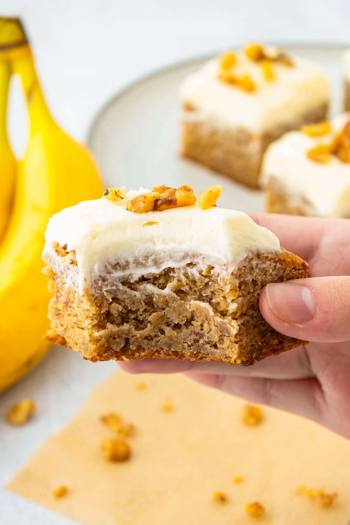a hand holding up Banana Bars in hand with a bite taken out