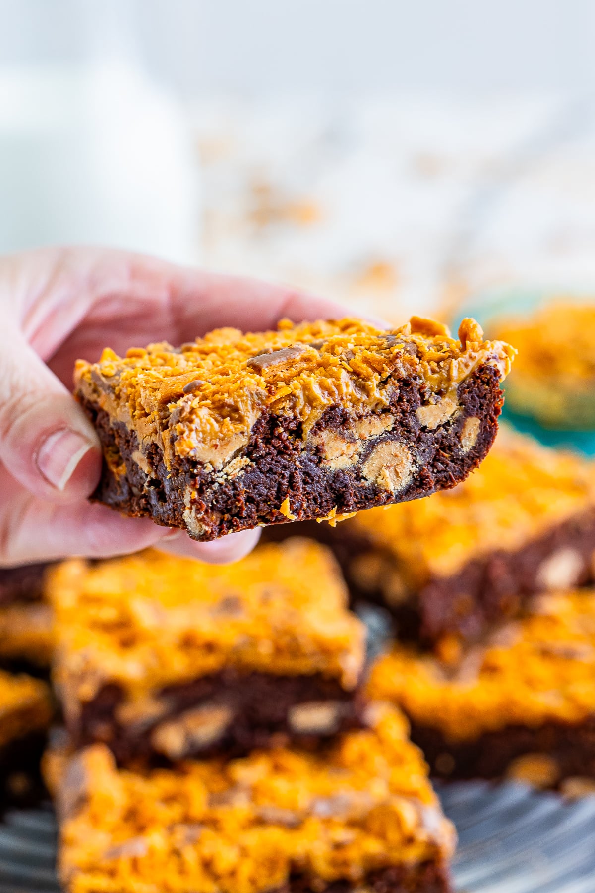 a hand holding up Butterfinger Brownies in air