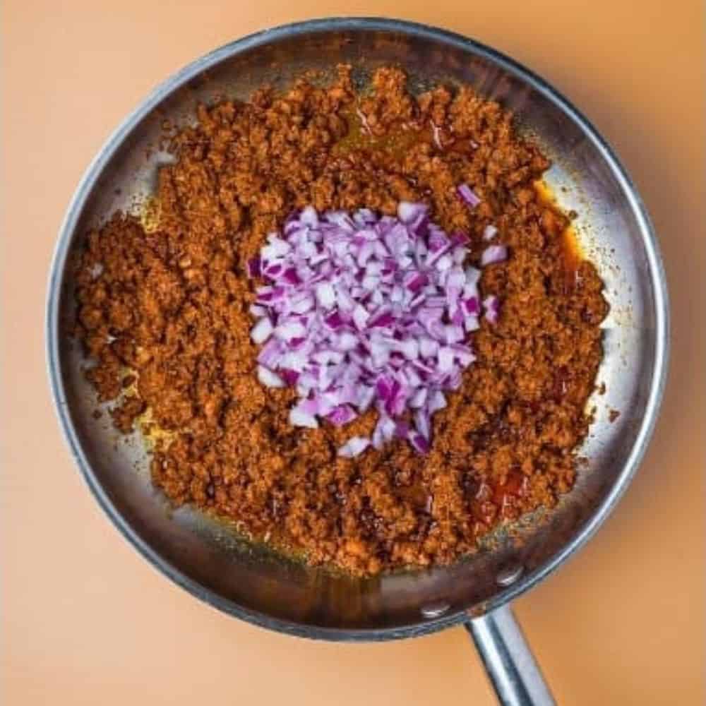 chopped red onions added to the pan with cooked chorizo.