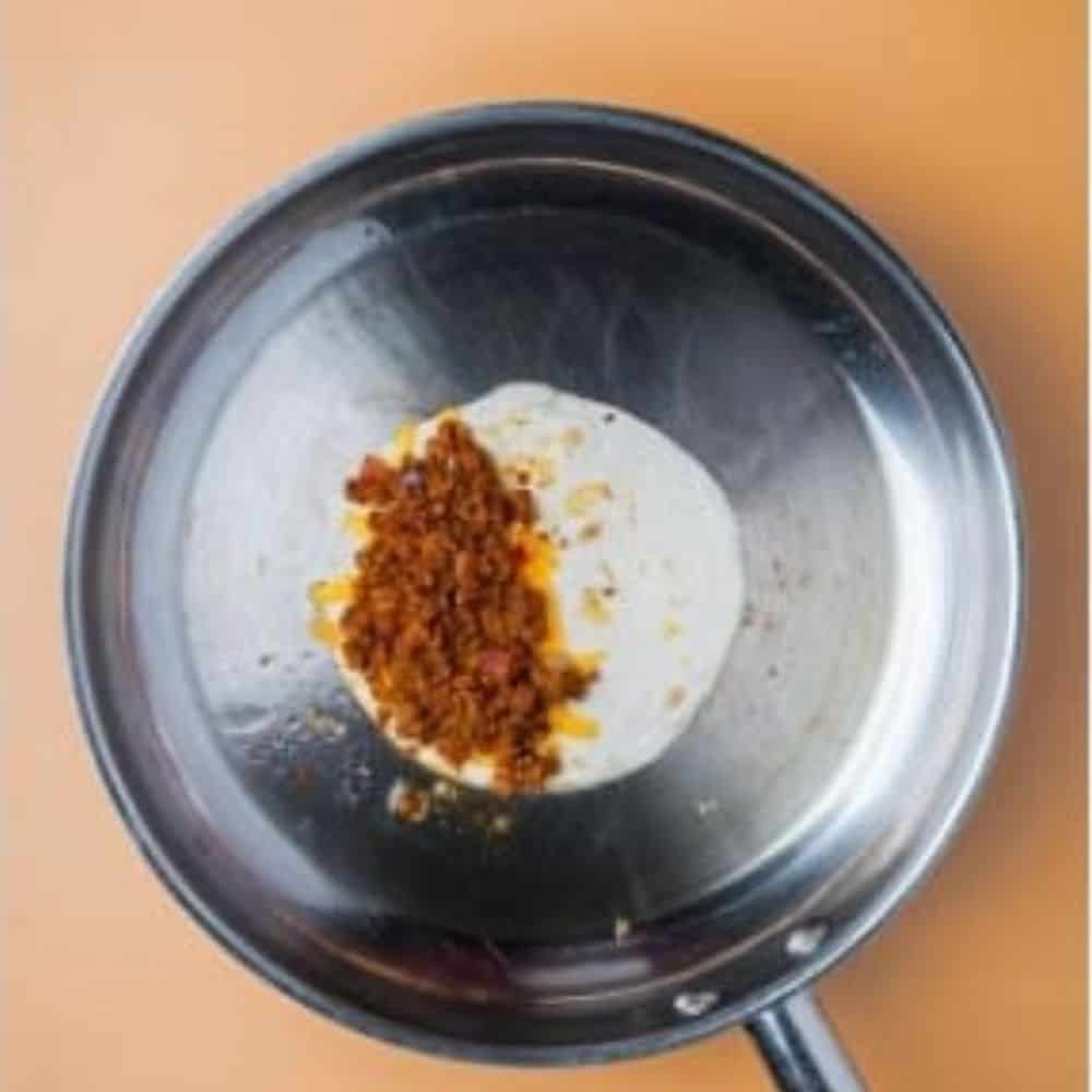 tortilla in a pan stuffed with cheese and cooked chorizo mixture.