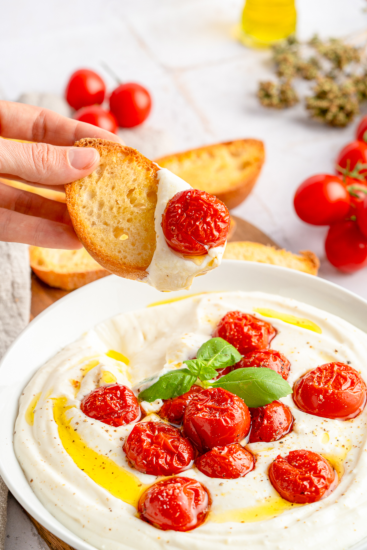 a hand holding a piece of bread in air with Whipped Ricotta Cheese on it