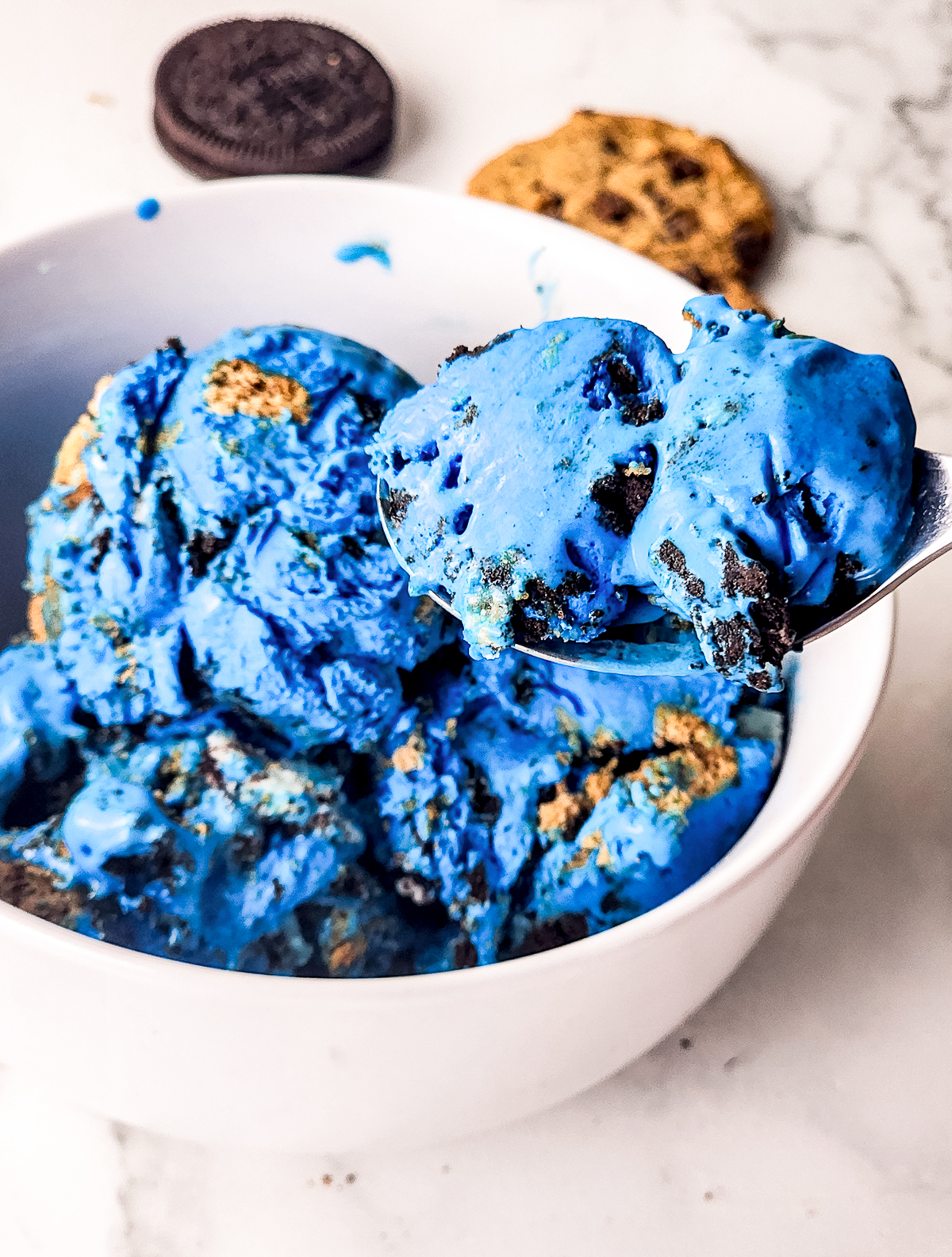 a spoon holding up a bite of Cookie Monster Ice Cream  in air