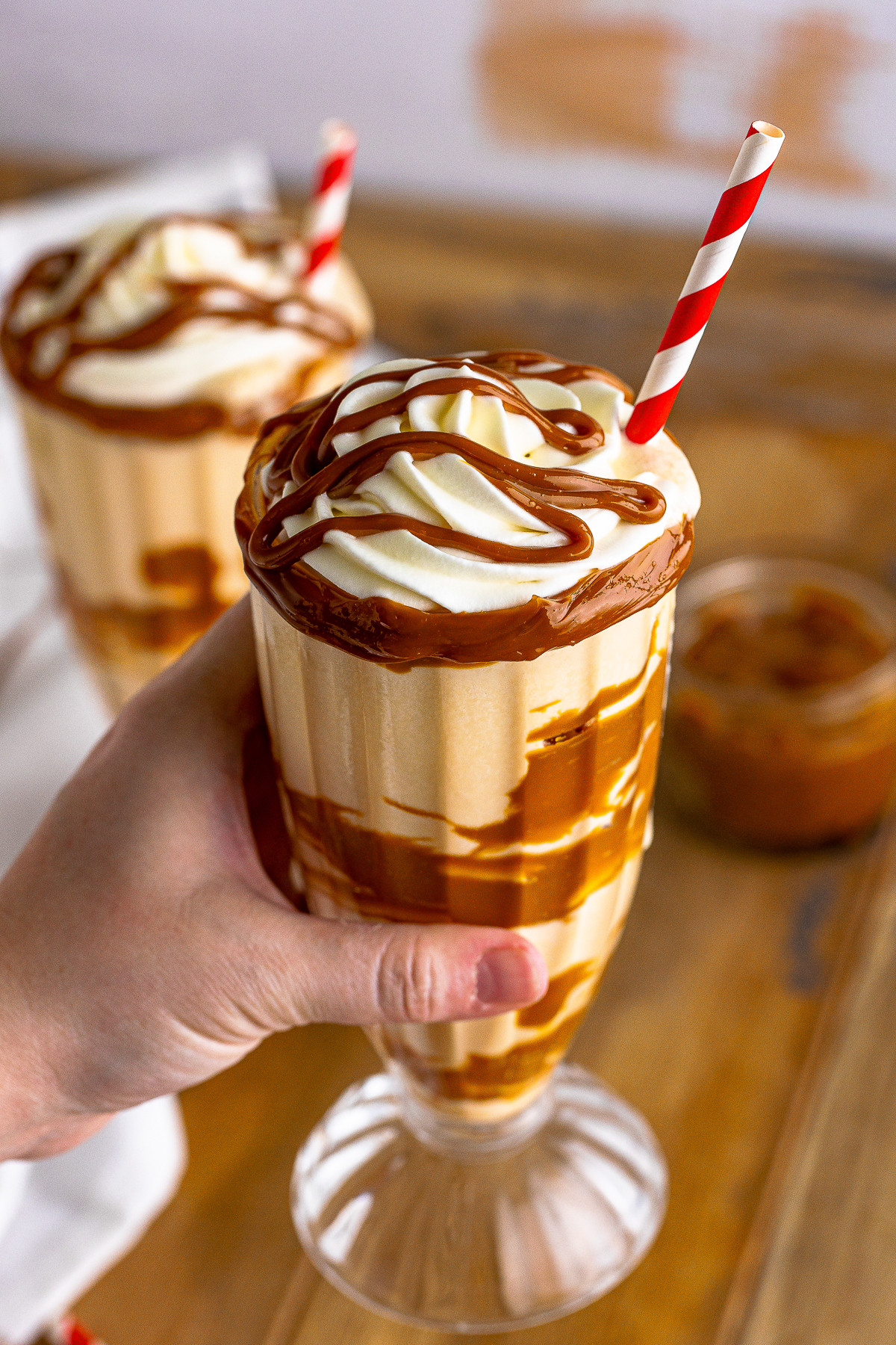 a hand holding up a Dulce de Leche Milkshake in air