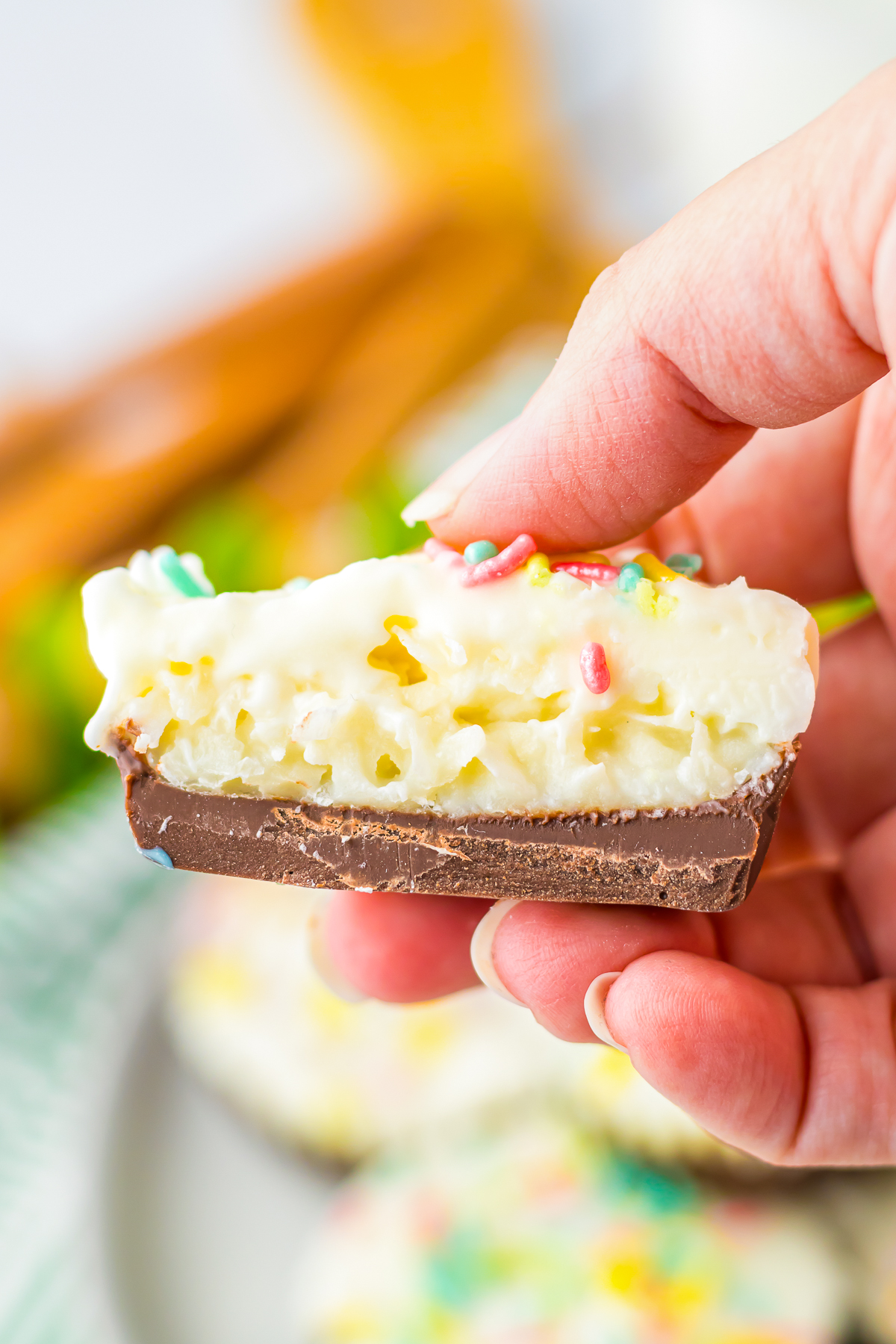 a hand holding up a piece of Coconut Candy that has been cut in half