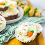 A finished Coconut Candy cup topped with white chocolate and pastel sprinkles on a wooden board.