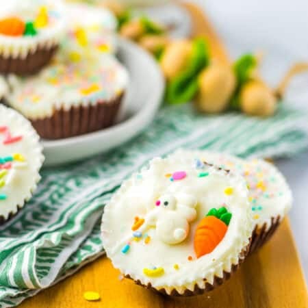 A finished Coconut Candy cup topped with white chocolate and pastel sprinkles on a wooden board.