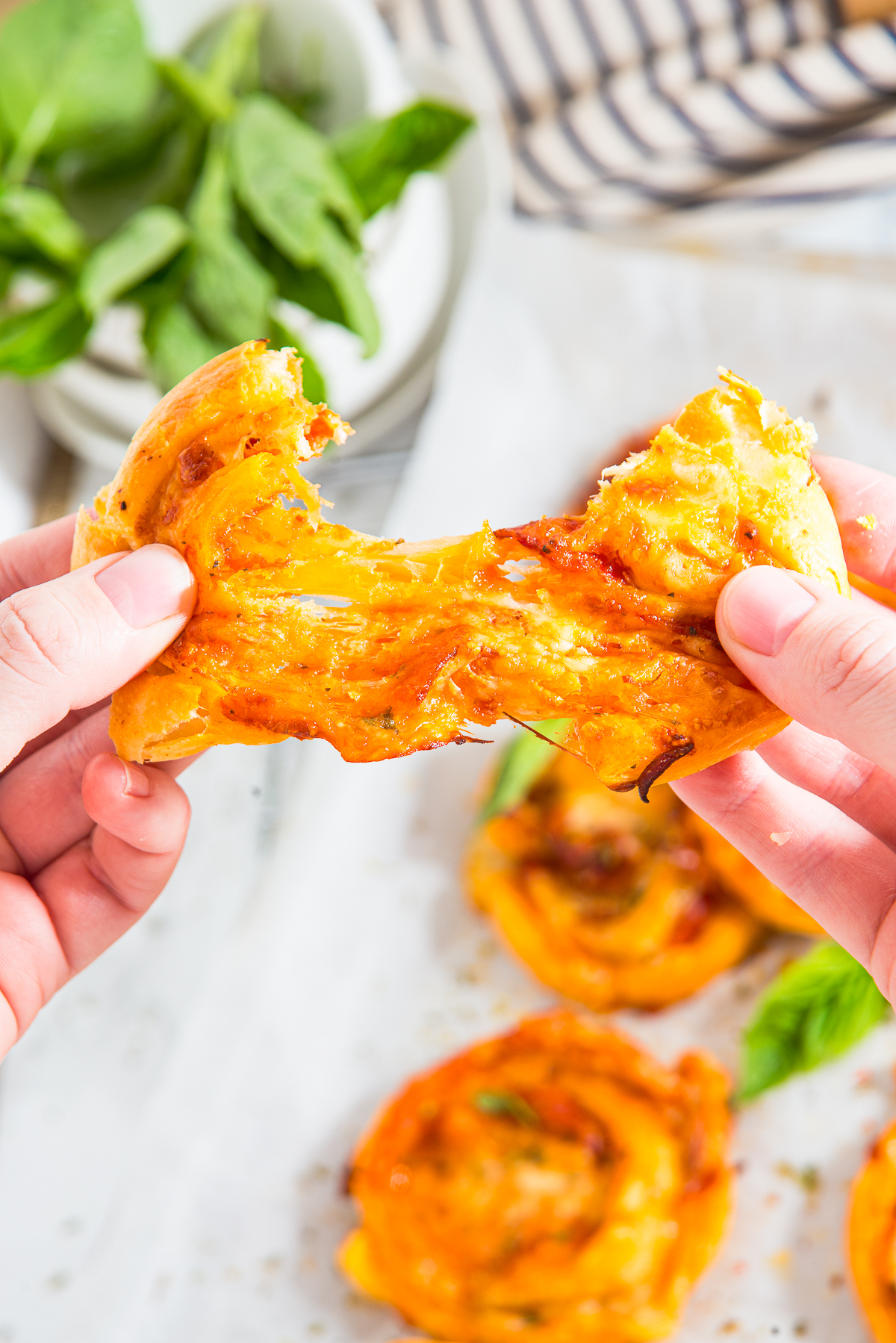a hand pulling apart Pepperoni Rolls with melty cheese