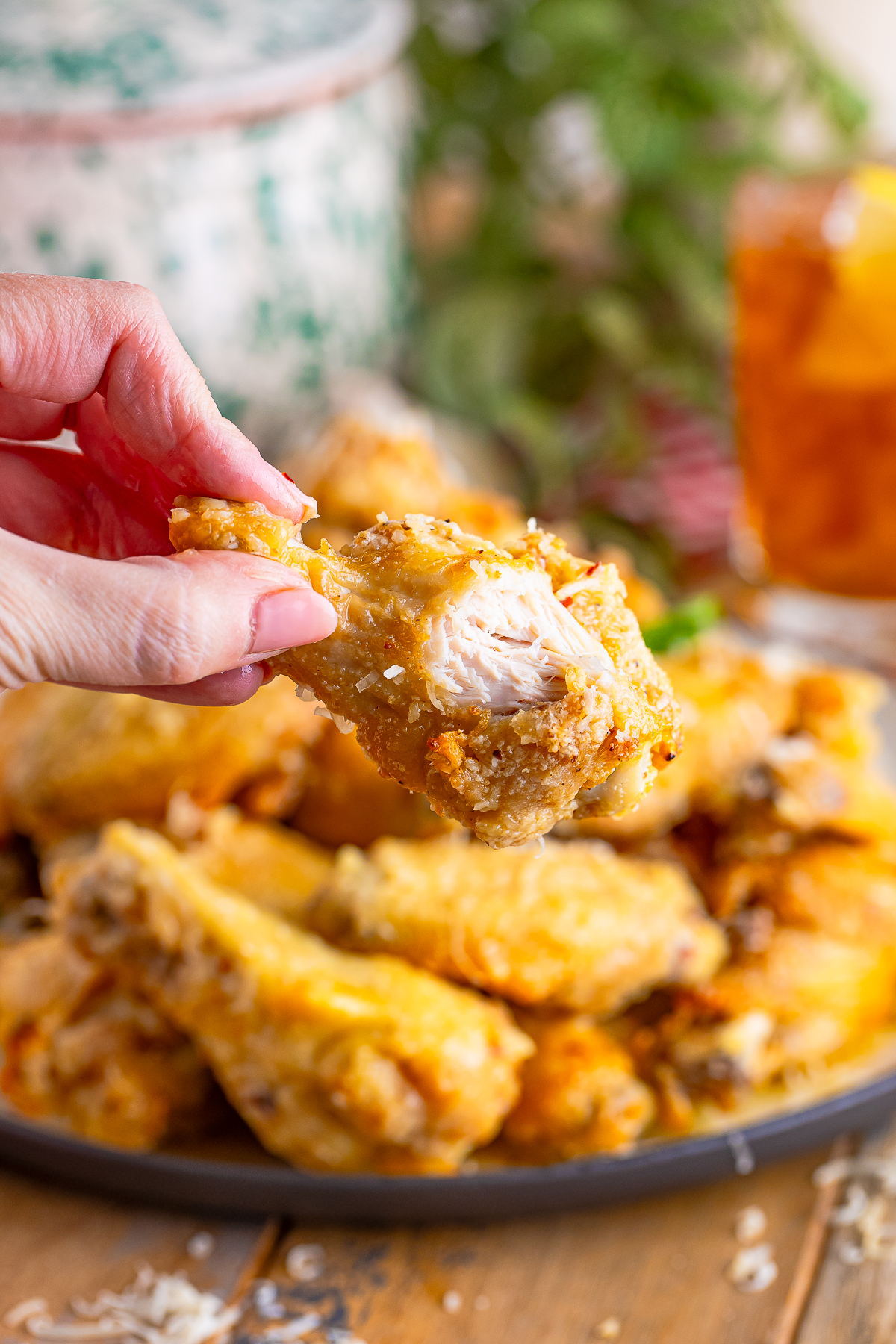 a hand holding up Garlic Parmesan Hot Wings in air with a bite taken out