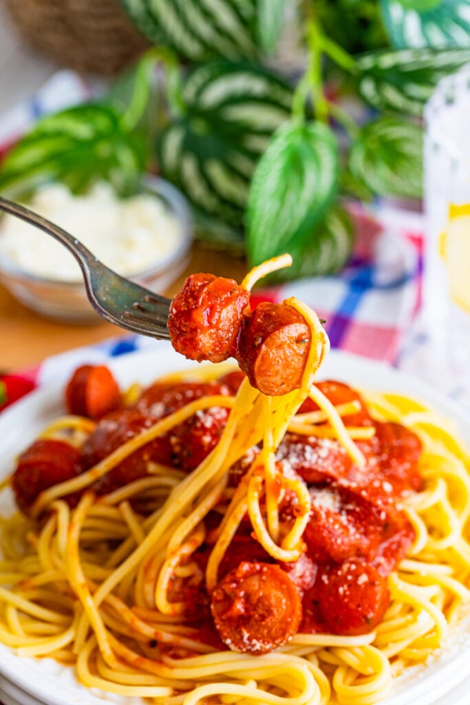 a fork holding up a bite of Hot Dogs Spaghetti in air
