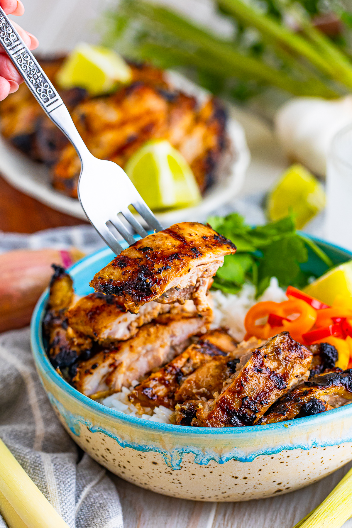 a fork holding up a piece of Lemongrass Chicken in air
