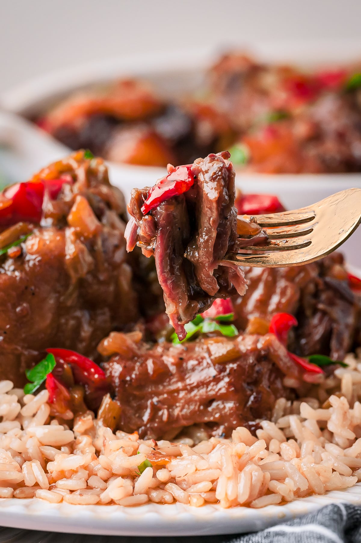 a fork holding up a bite of Oxtails in air