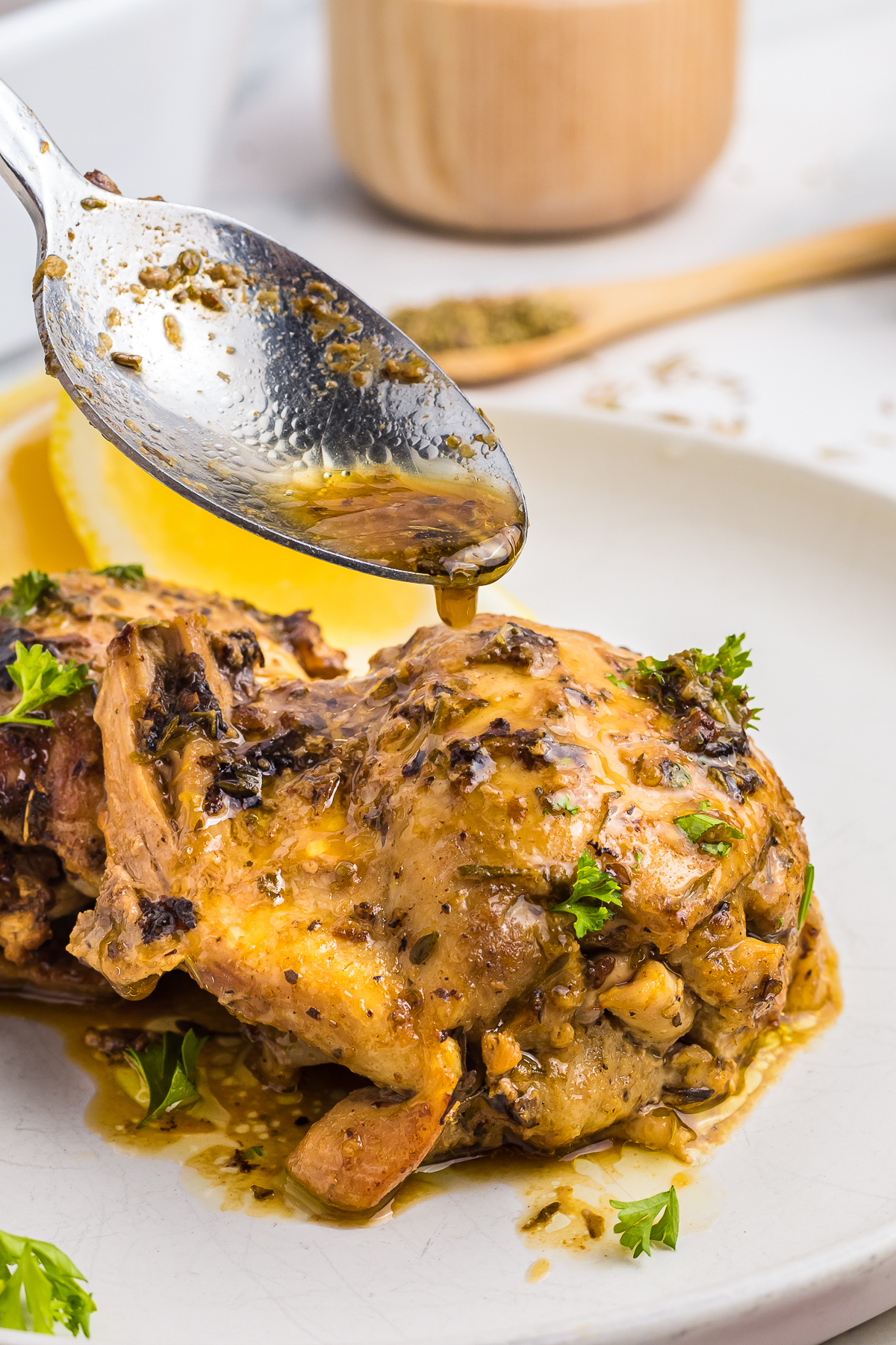 a spoon pouring sauce over Marinaded Chicken Thighs