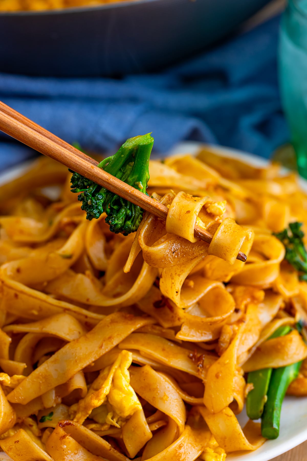 chopsticks holding up a bite of Thai Pad See Ew over a plate