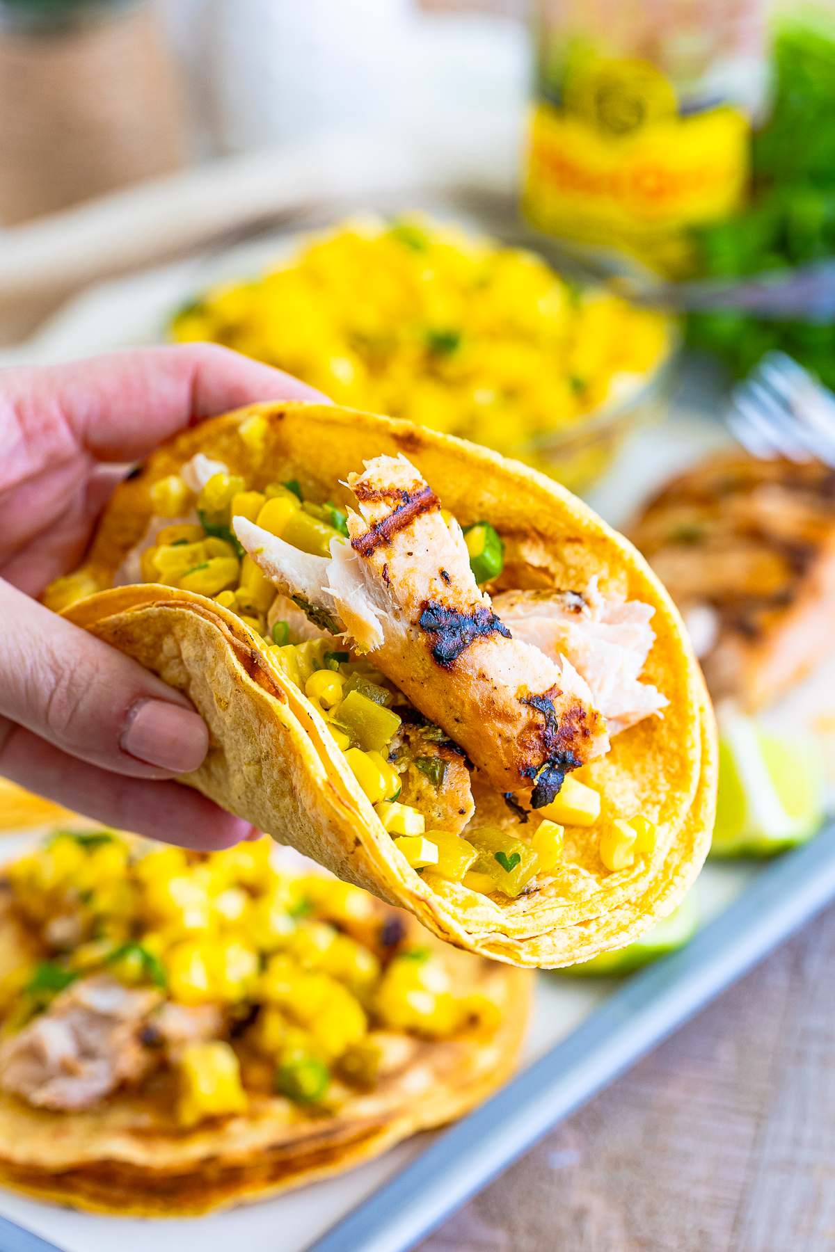a hand holding up Mahi Fish Tacos in air