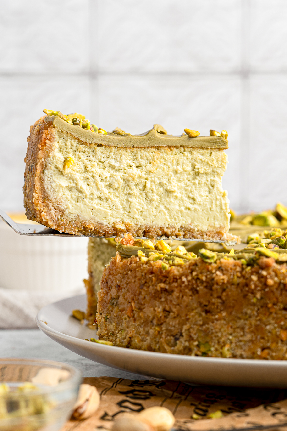 a slice of Pistachio Cheesecake in air on a cake server