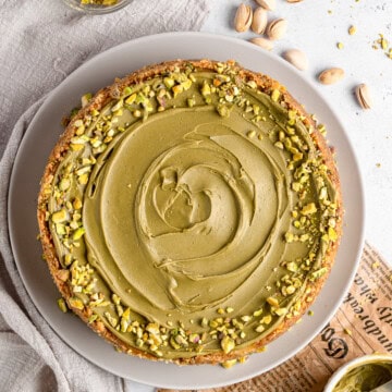 A whole creamy pistachio cheesecake topped with pistachio spread and chopped pistachios.