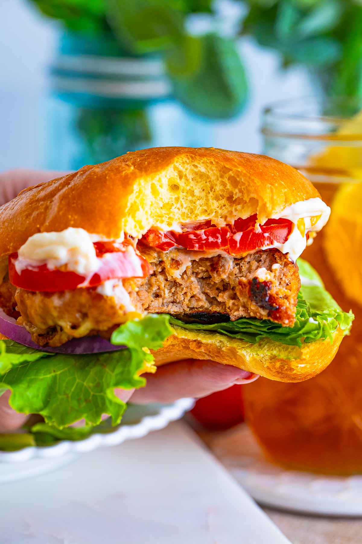 a hand holding up a turkey burger recipe with a bite taken out in air