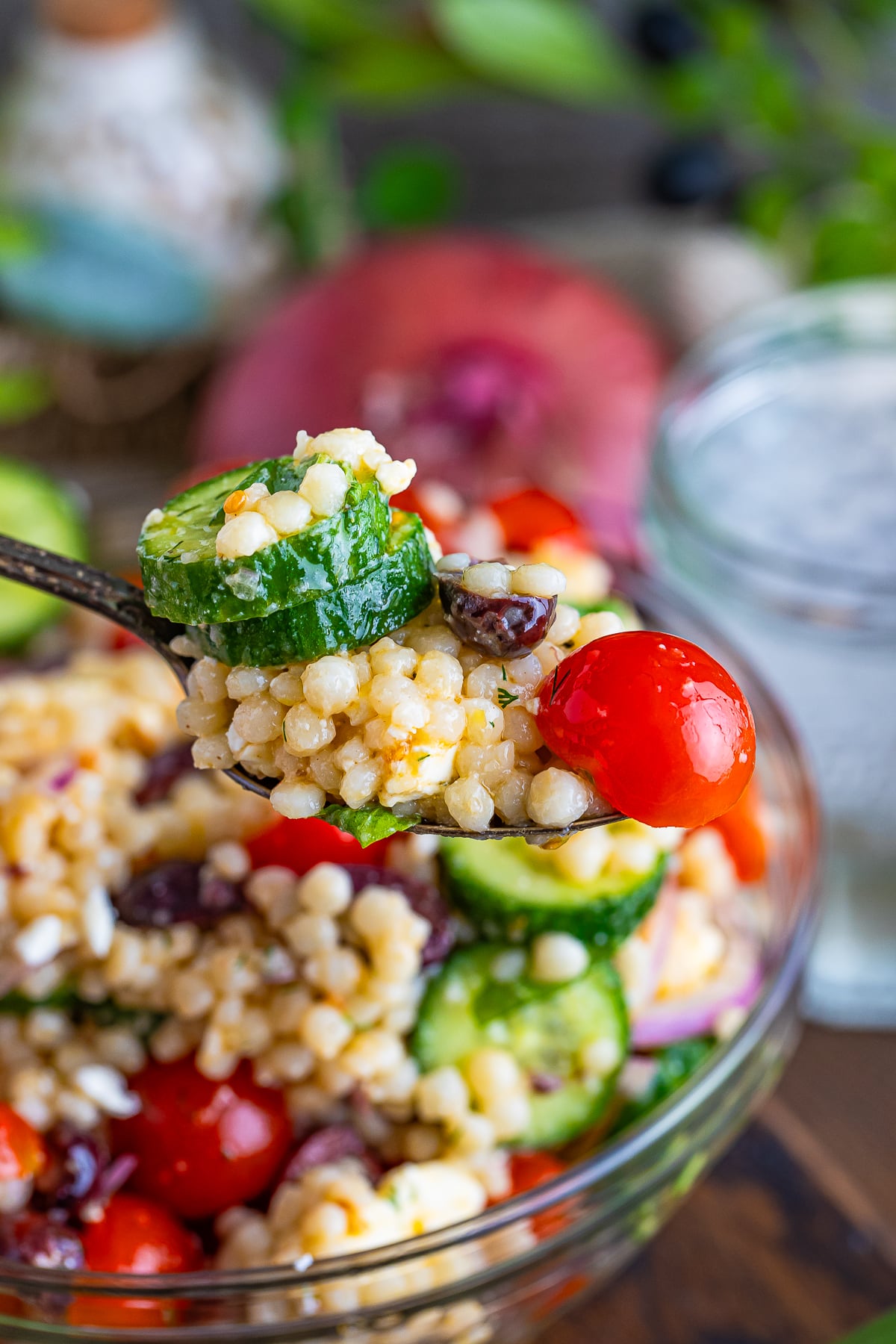 a spoon holding up a spoonful of Couscous Salad in air
