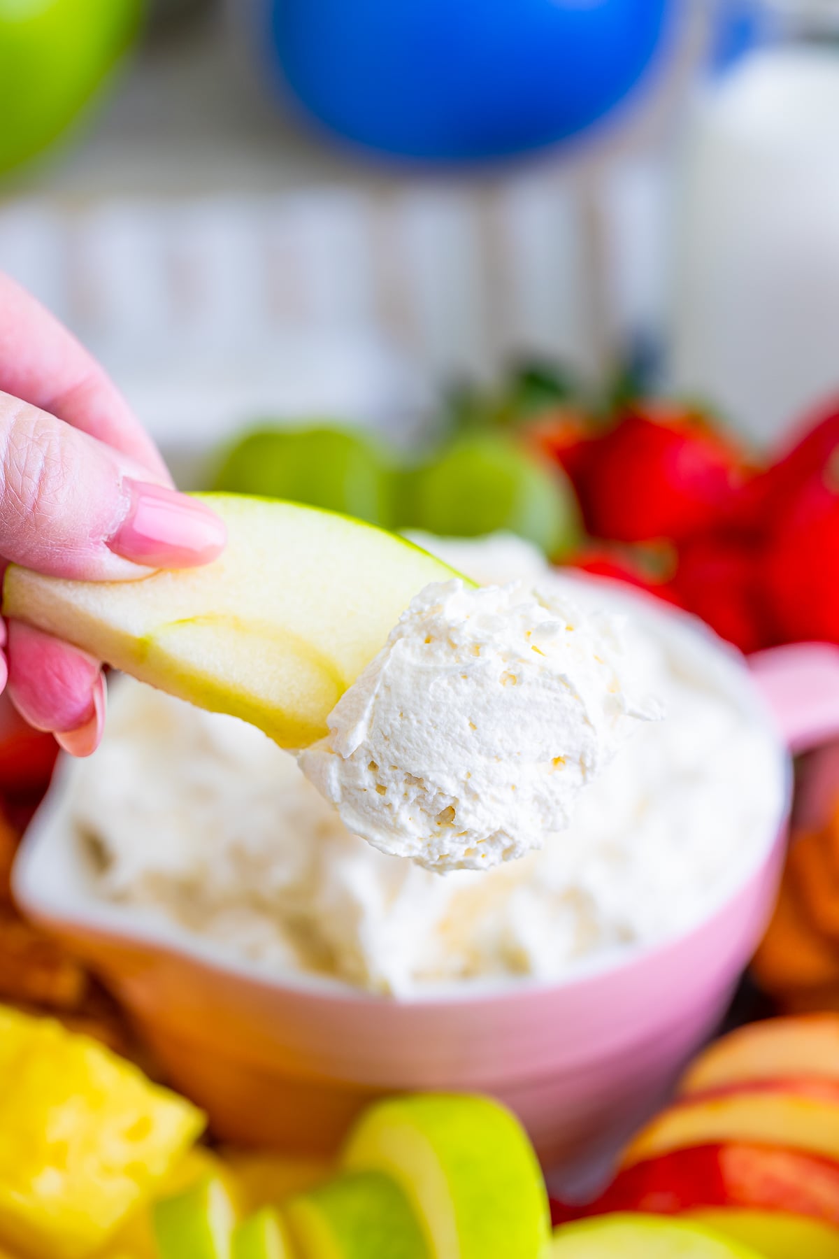 a hand holding up a slice of apple with Cream Cheese Fruit Dip in air