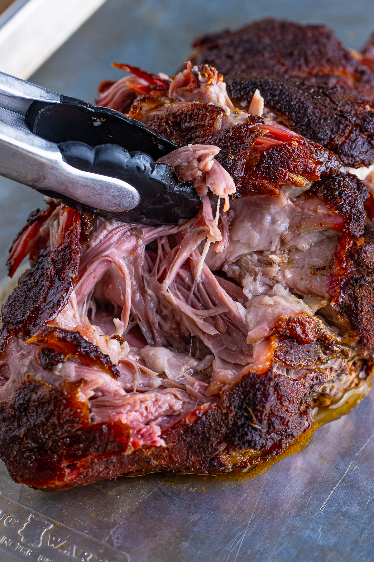 a pair of tongs shredding Pulled Pork