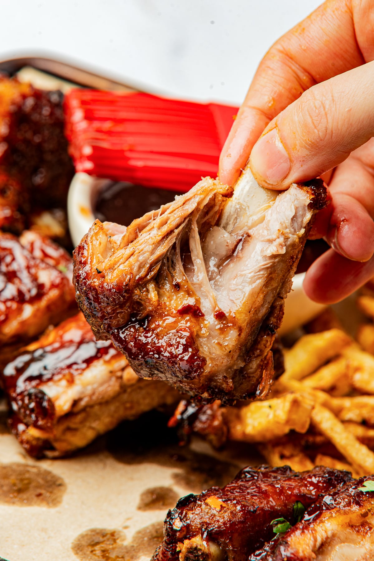 a hand holding up St Louis Ribs in air with the meat falling off