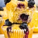 A lemon blueberry muffin with a bite taken out showing the juicy blueberries inside.