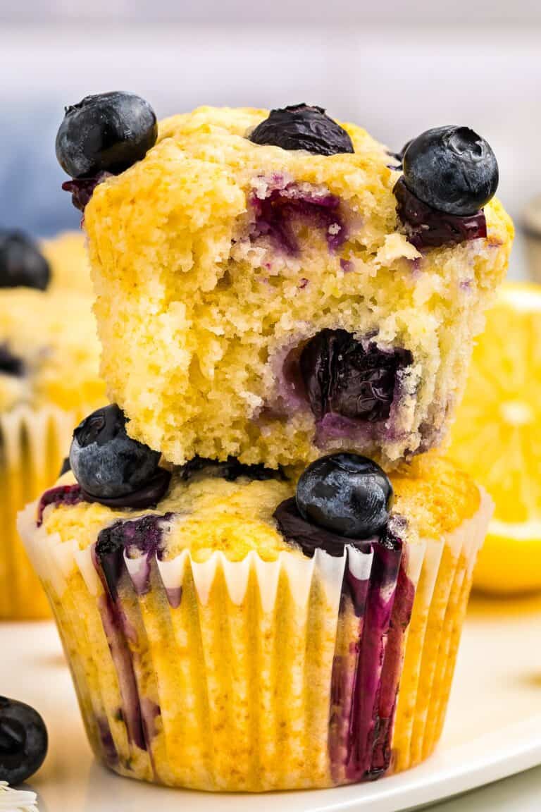 A lemon blueberry muffin with a bite taken out showing the juicy blueberries inside.