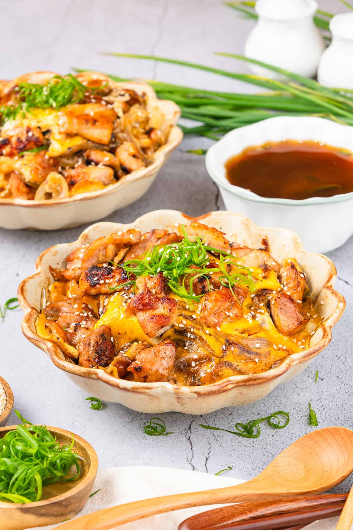 Oyakodon chicken and egg rice bowl served with a side of sauce.