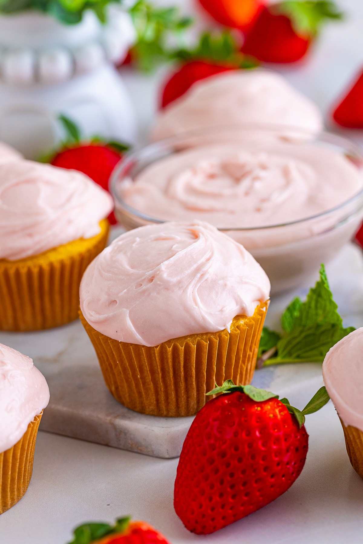 a cupcake topped with Strawberry Cream Cheese Frosting on a serving board