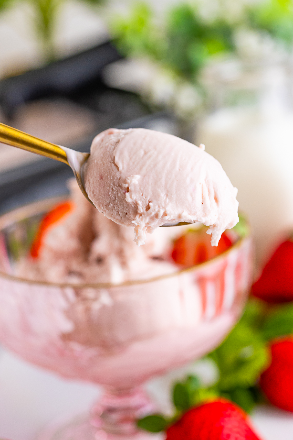 a spoon holding up a bite of Strawberry ice cream in air