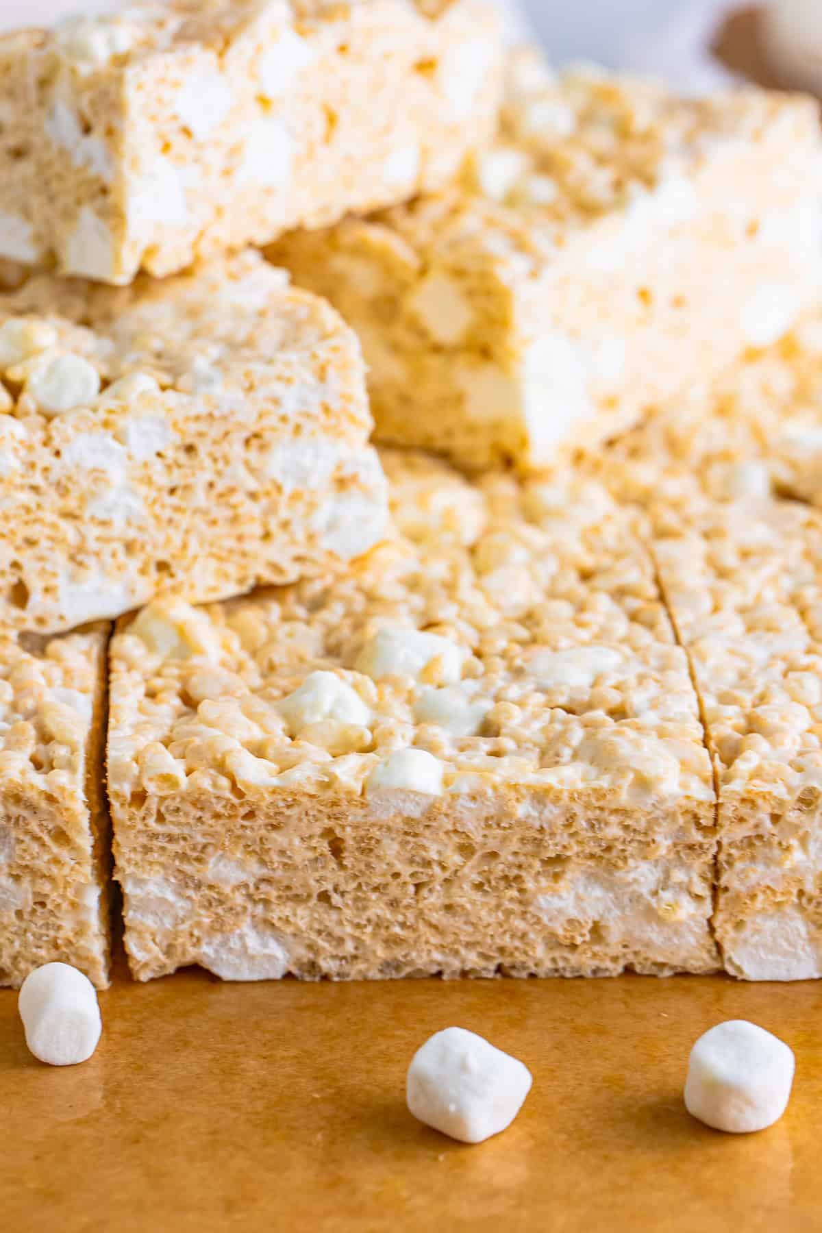 Stacked brown butter rice krispie treats with gooey marshmallow showing through on a wood board.
