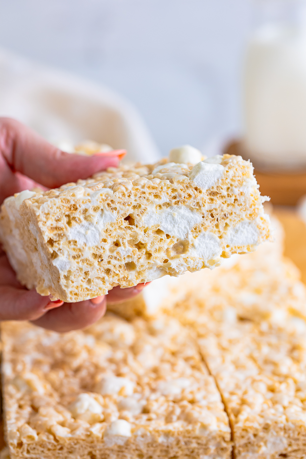 a hand holding up Brown Butter Rice Crispy Treats in air