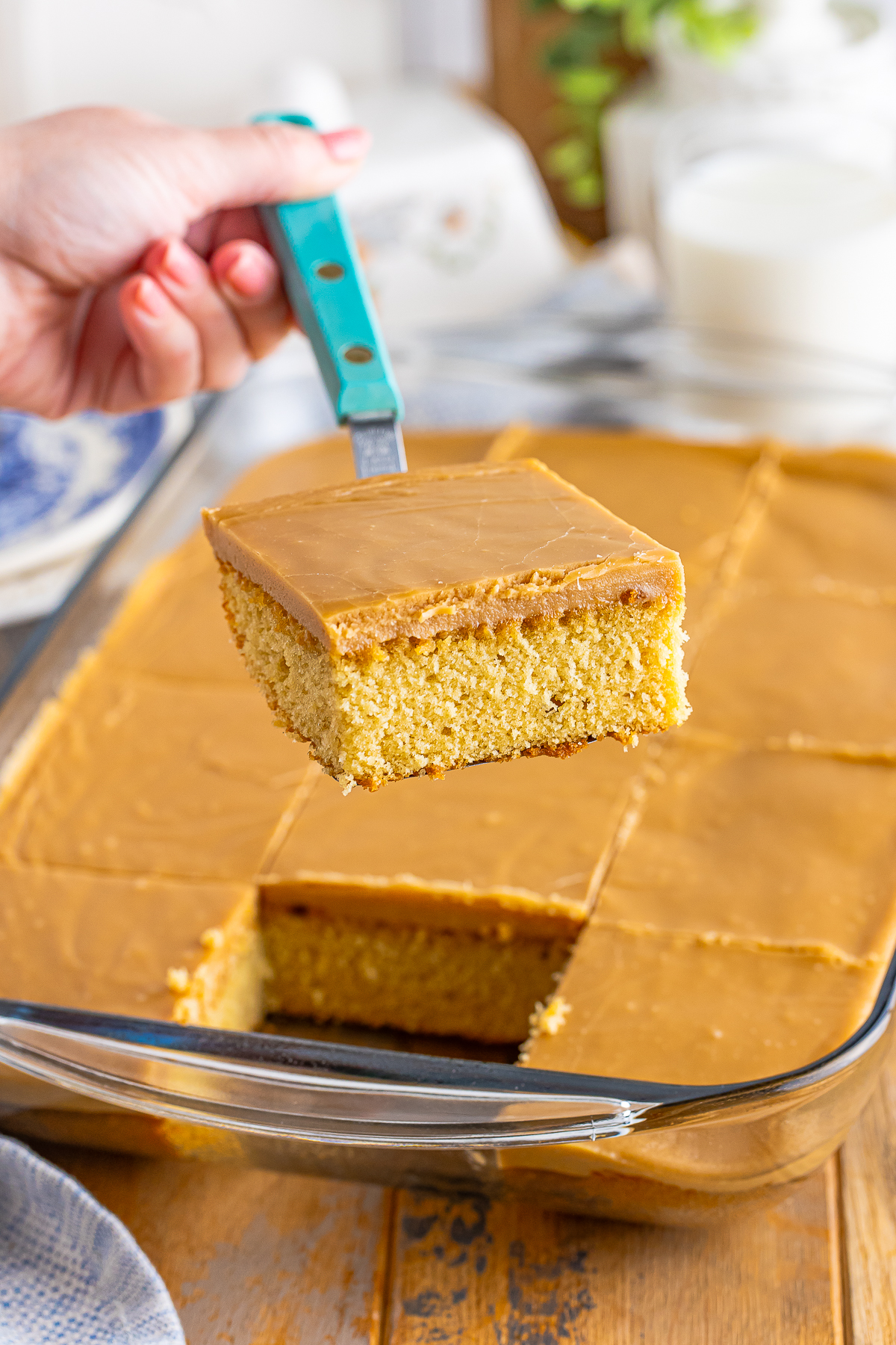 a hand holding up a spatula that has a piece of Caramel Cake on it