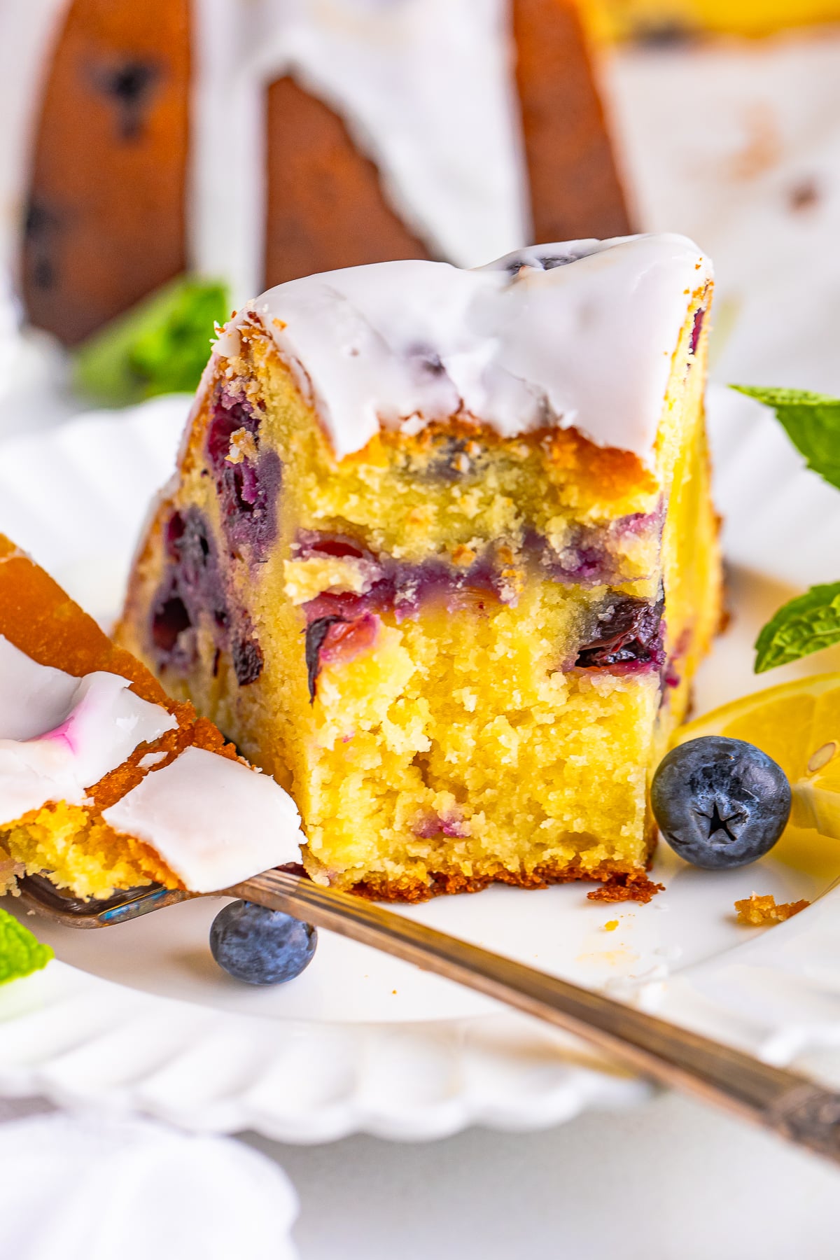 a slice of lemon blueberry pound cake on a plate with a bite taken out