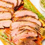 Sliced grilled London broil on a wood board showing a juicy medium rare interior, made with this London broil marinade.