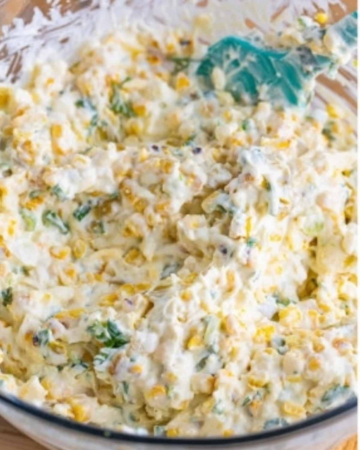 a bowl filled with mix of grilled corn, herbs and cream cheese.