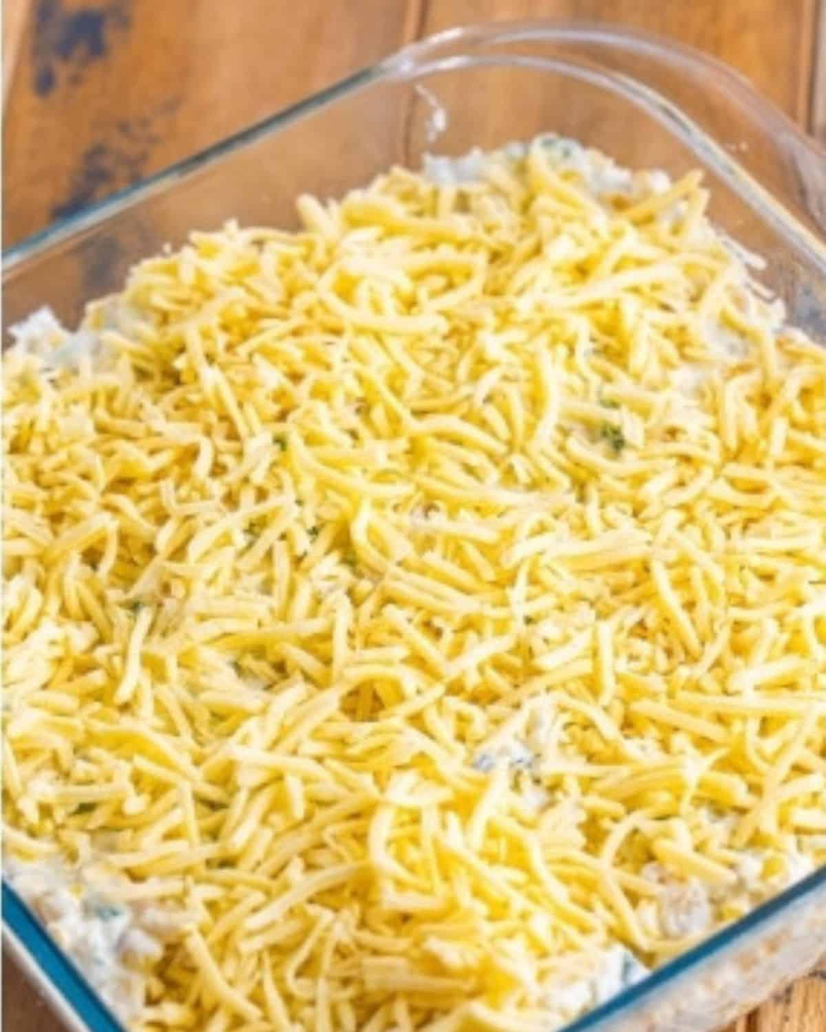 mexican street corn dip in a baking dish, topped with shredded cheese.