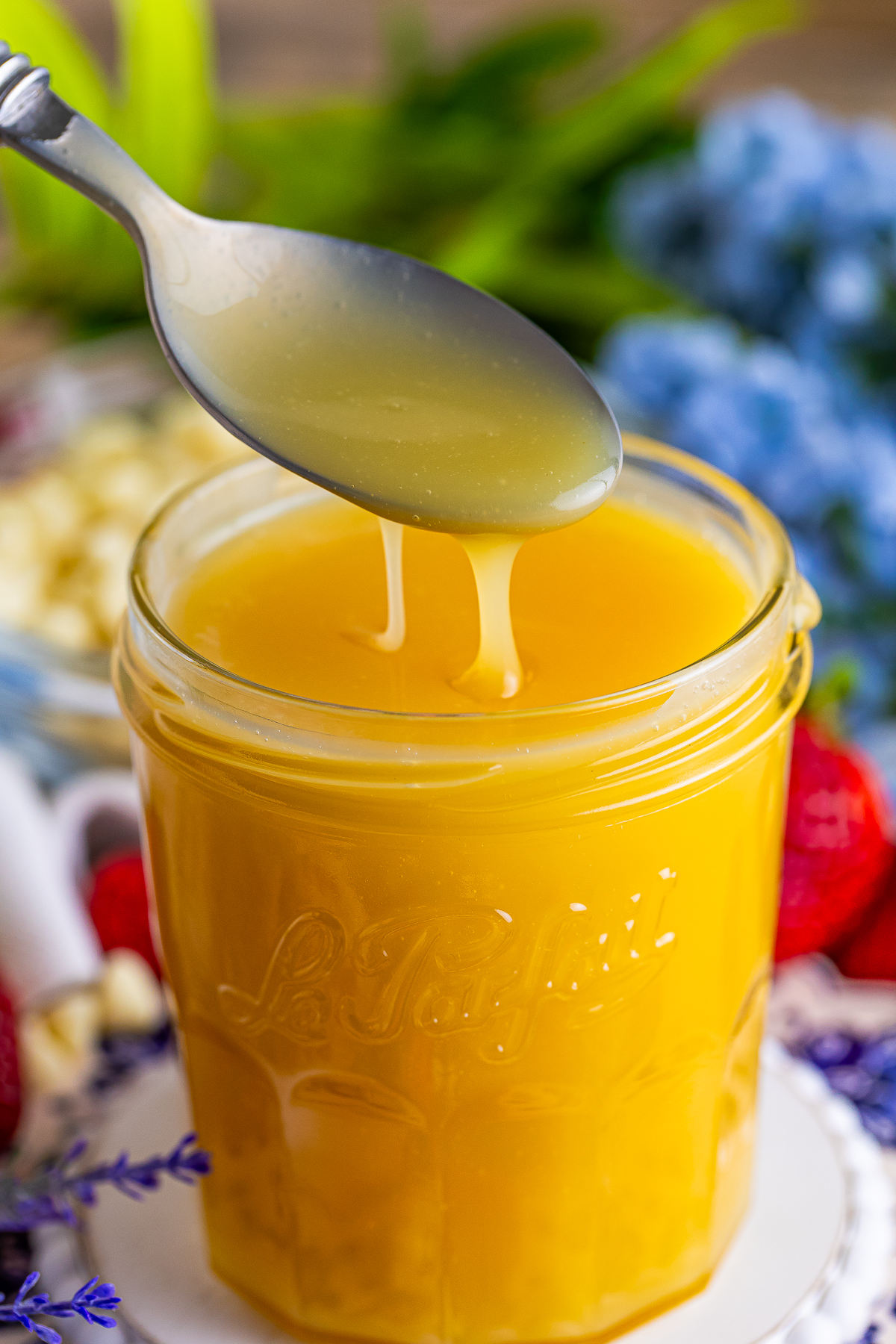 a spoon drizzling White Chocolate Sauce into a glass jar